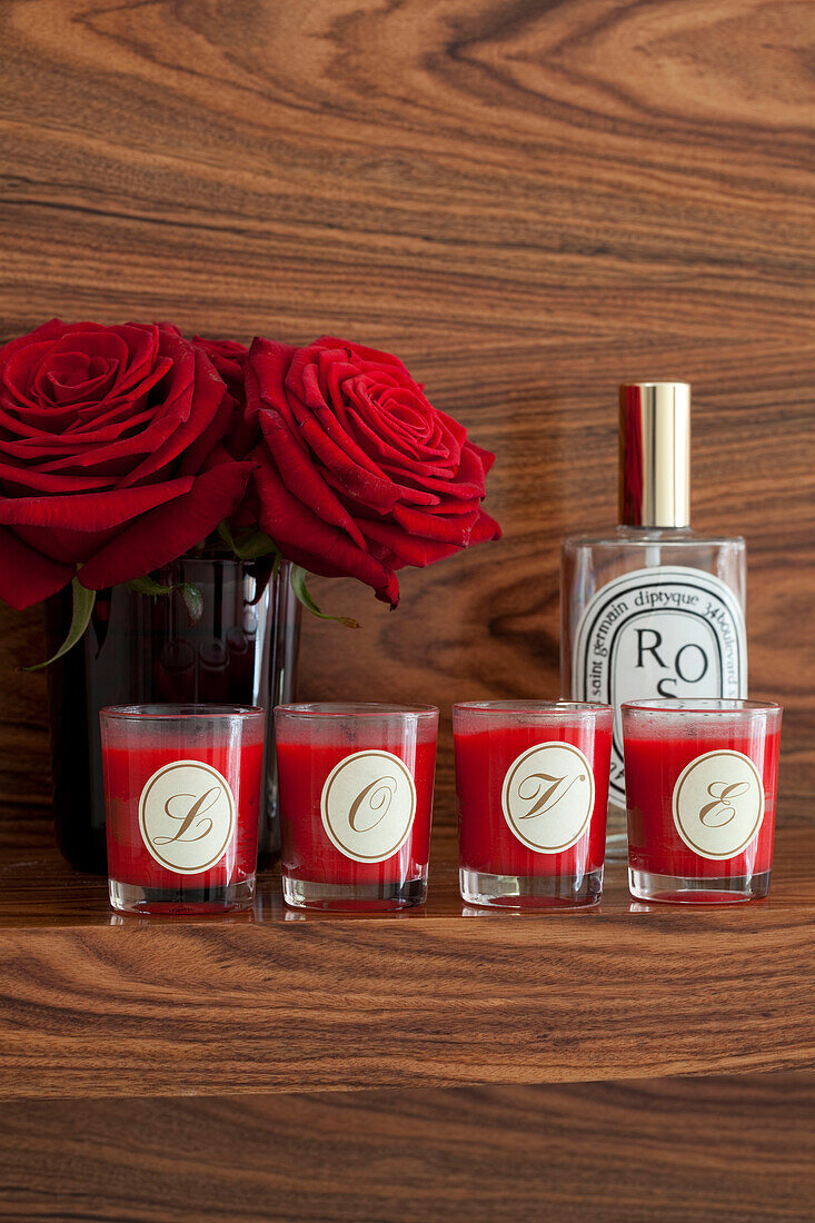 Red roses and scented candles with perfume bottle London UK