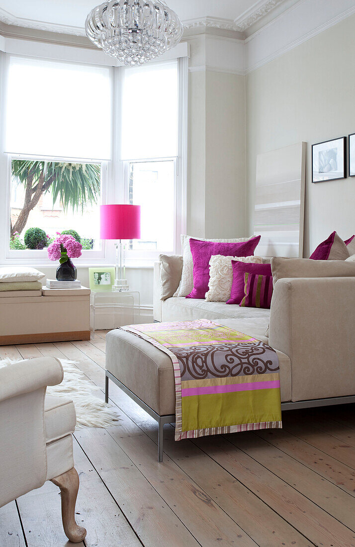 Patterned fabric on footstool in white and pink living room of contemporary London home, UK