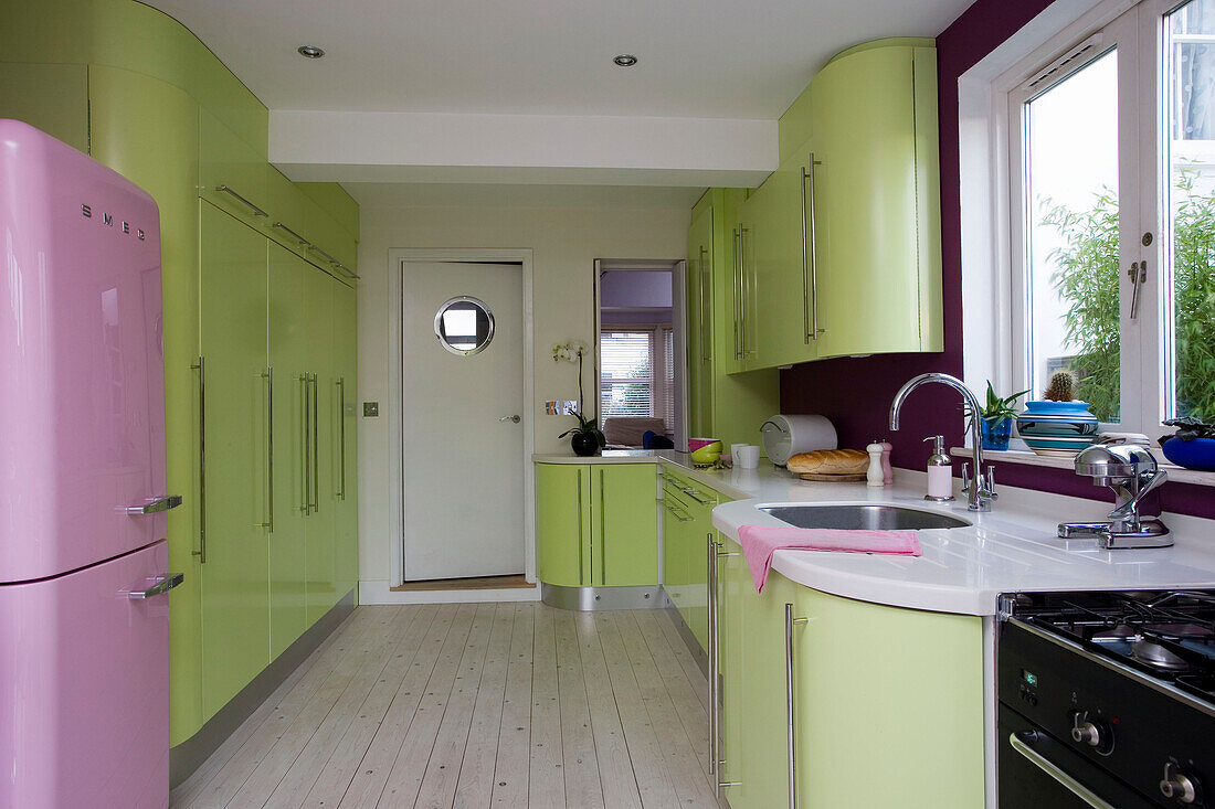Lindgrüne Küche im Retrostil mit rosa Kühlschrank in einem Haus in East Sussex, England, UK