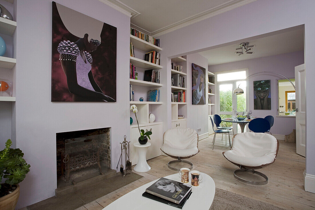 Weiße Vintage-Lederstühle im offenen Wohn- und Esszimmer mit eingelassenen Bücherregalen in einem Haus in East Sussex, England, UK