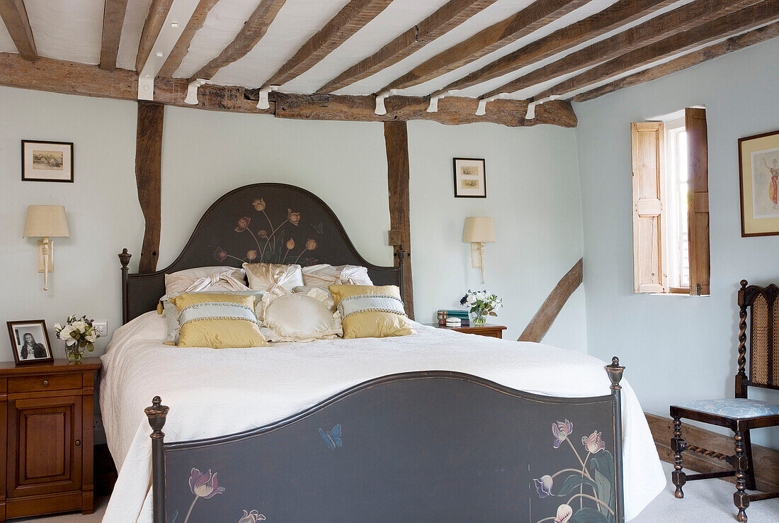 Handbemaltes Kopf- und Fußteil eines Doppelbettes in einem Haus mit Holzrahmen in Surrey UK