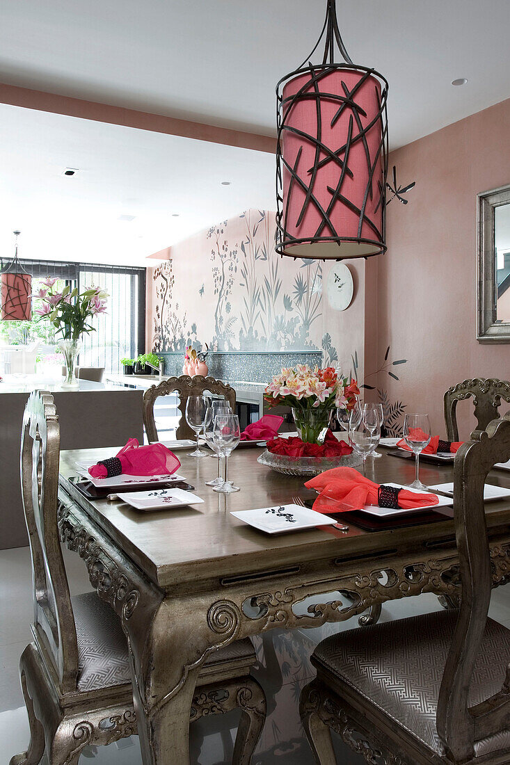 Square dining table with metallic finish under metal worked ceiling lamp in contemporary London townhouse, England, UK
