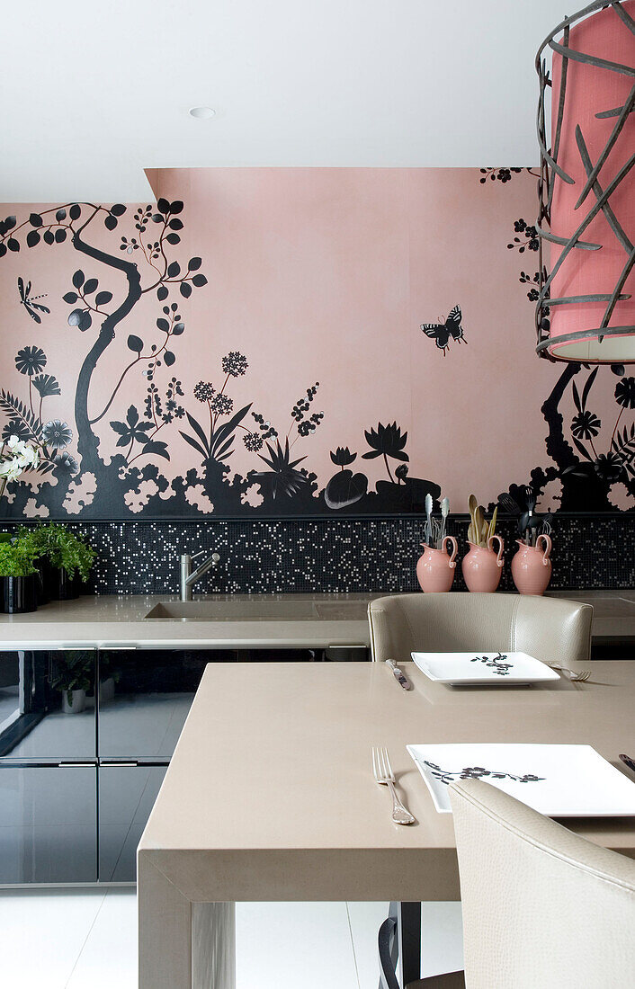 Place settings at table in pink kitchen with black wall decor in contemporary London townhouse, England, UK