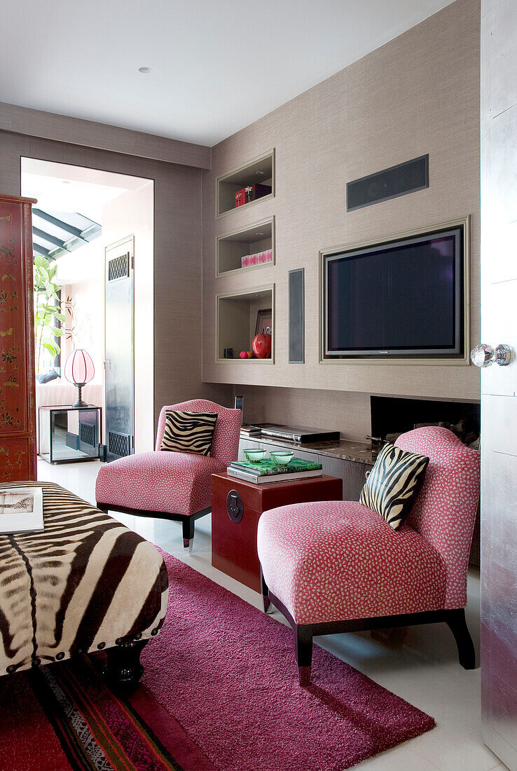 Upholstered matching chairs and plasma screen in bespoke wall detail in contemporary London townhouse, England, UK