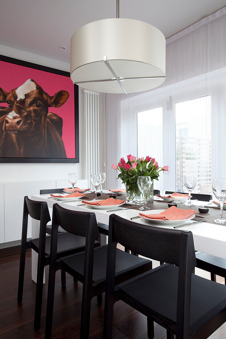 Dining room table with large picture of cow in harness, contemporary home, Hove, East Sussex, England, UK