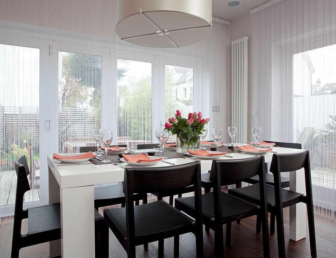 Black and white dining table in garden extension of contemporary home, Hove, East Sussex, England, UK