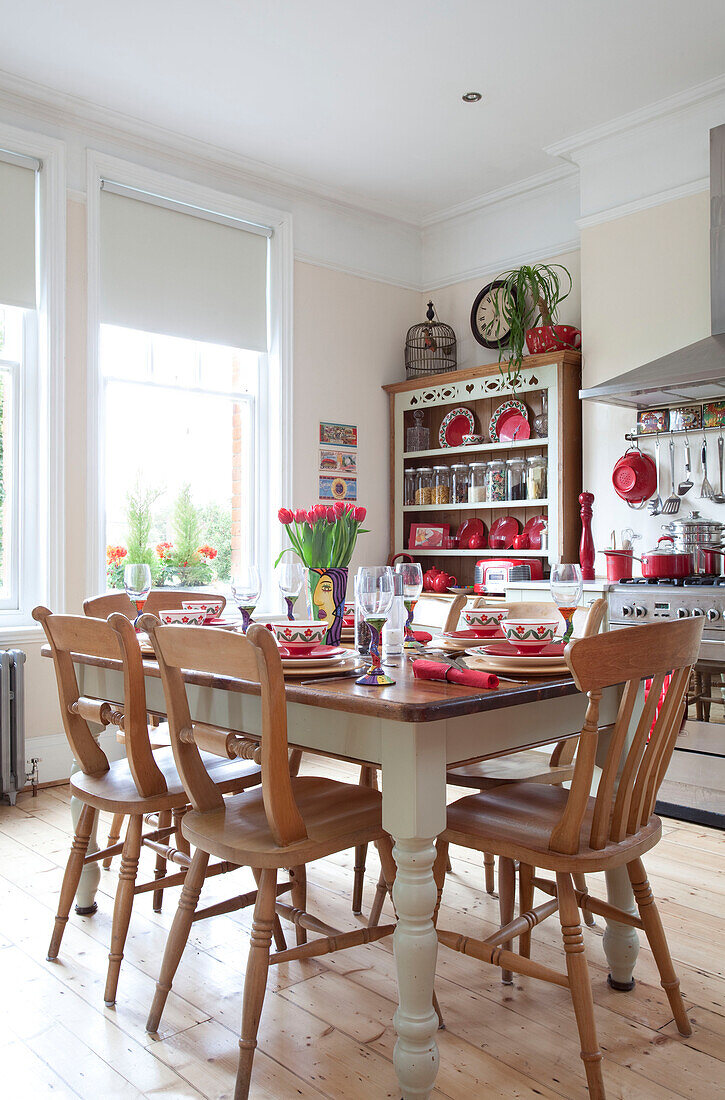 Sunlit kitchen with wooden table and chairs set for a meal in London townhouse, England, UK