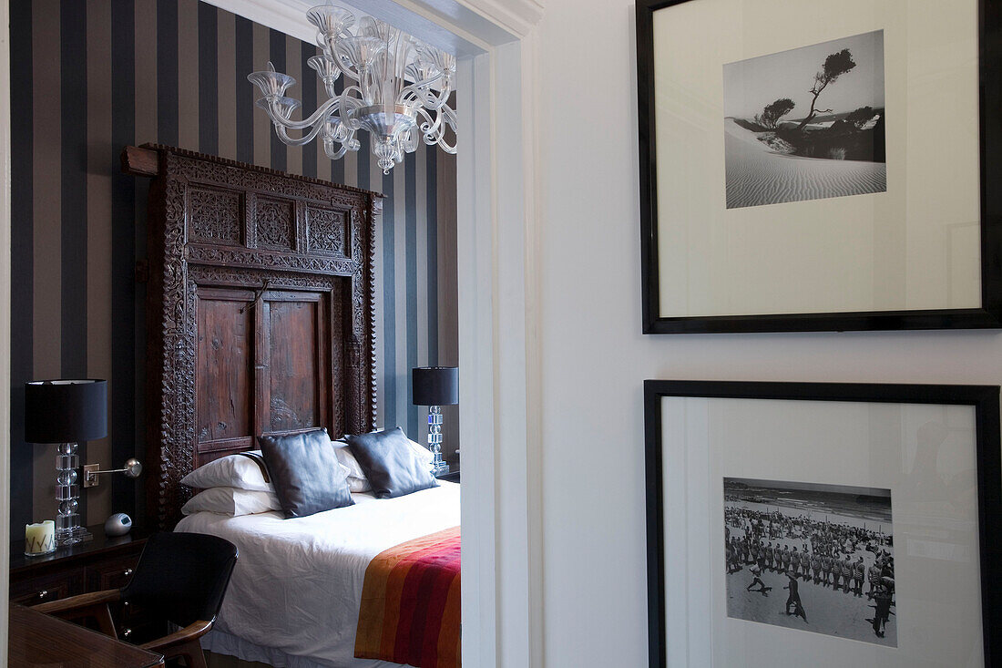 Striped wall paper and carved wooden headboard in London townhouse bedroom