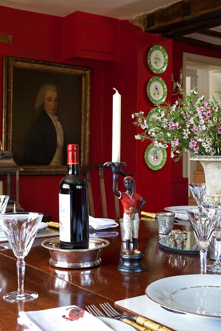 Rotwein und Gläser auf Esstisch mit Kunstwerk in Esszimmer in Kent England, UK