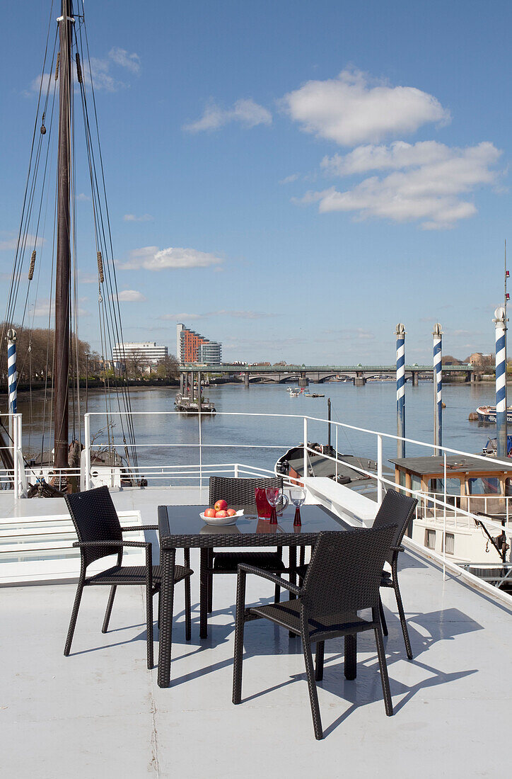 Table and chairs on London houseboat with view of river Thames