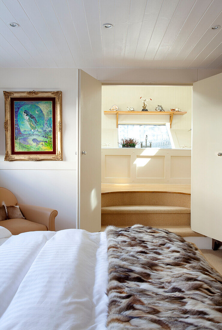 Pelzdecke auf einem Doppelbett mit Blick auf ein eigenes Badezimmer London UK