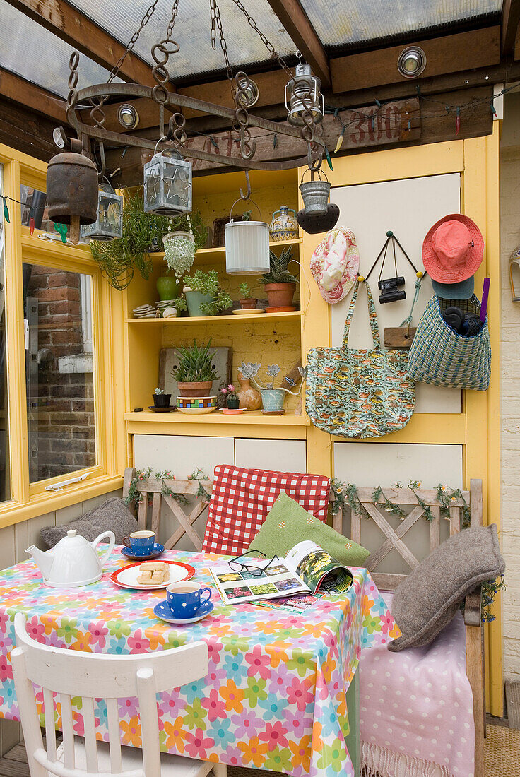 Sunhats and bags hang on wall above table in Rye home conservatory, East Sussex, England, UK