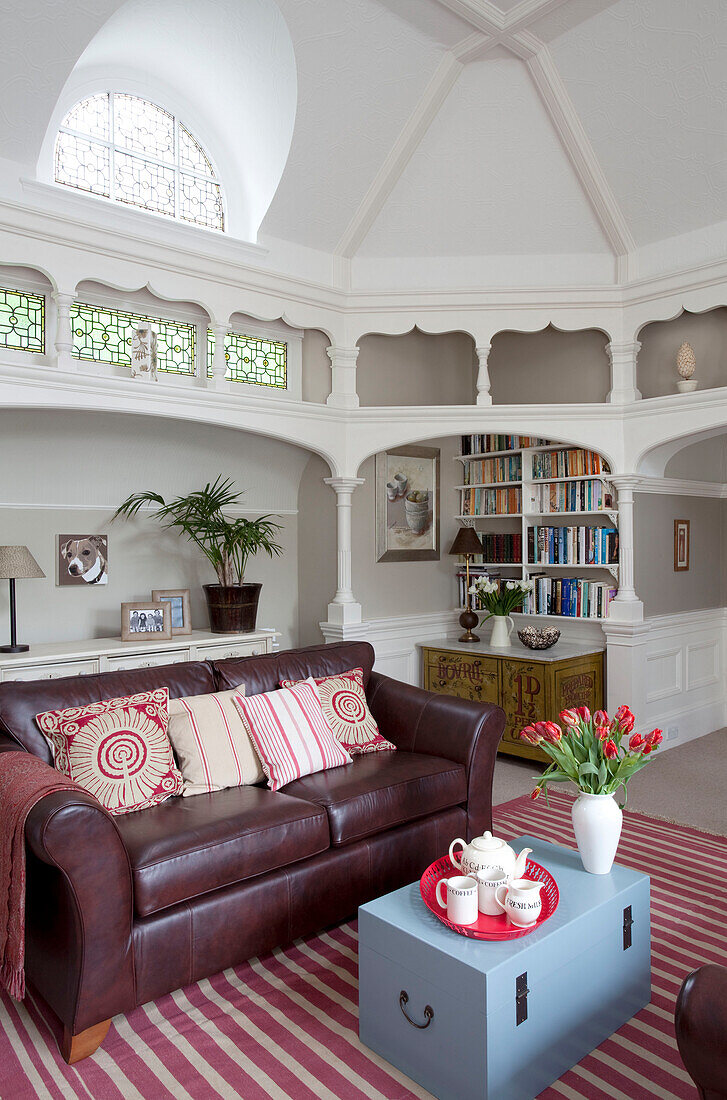 Braunes Ledersofa in einem architektonisch gestalteten Wohnzimmer mit eingelassenem Bücherregal in einem Haus in Surrey, England, Vereinigtes Königreich