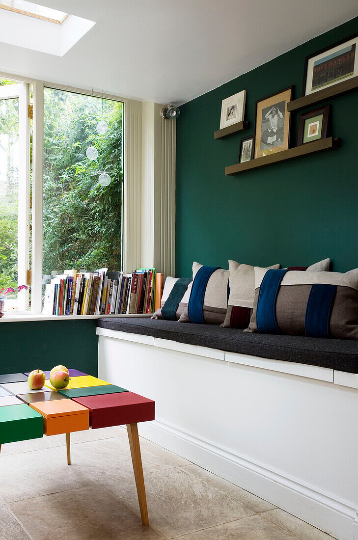 Cushions on grey bench seat with artwork and coffee table in London home, England, UK