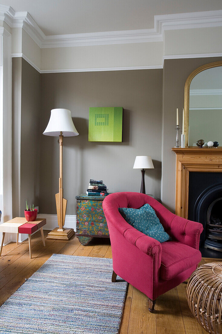 Pink armchair and standard lamp with white shade in living room of London home, England, UK