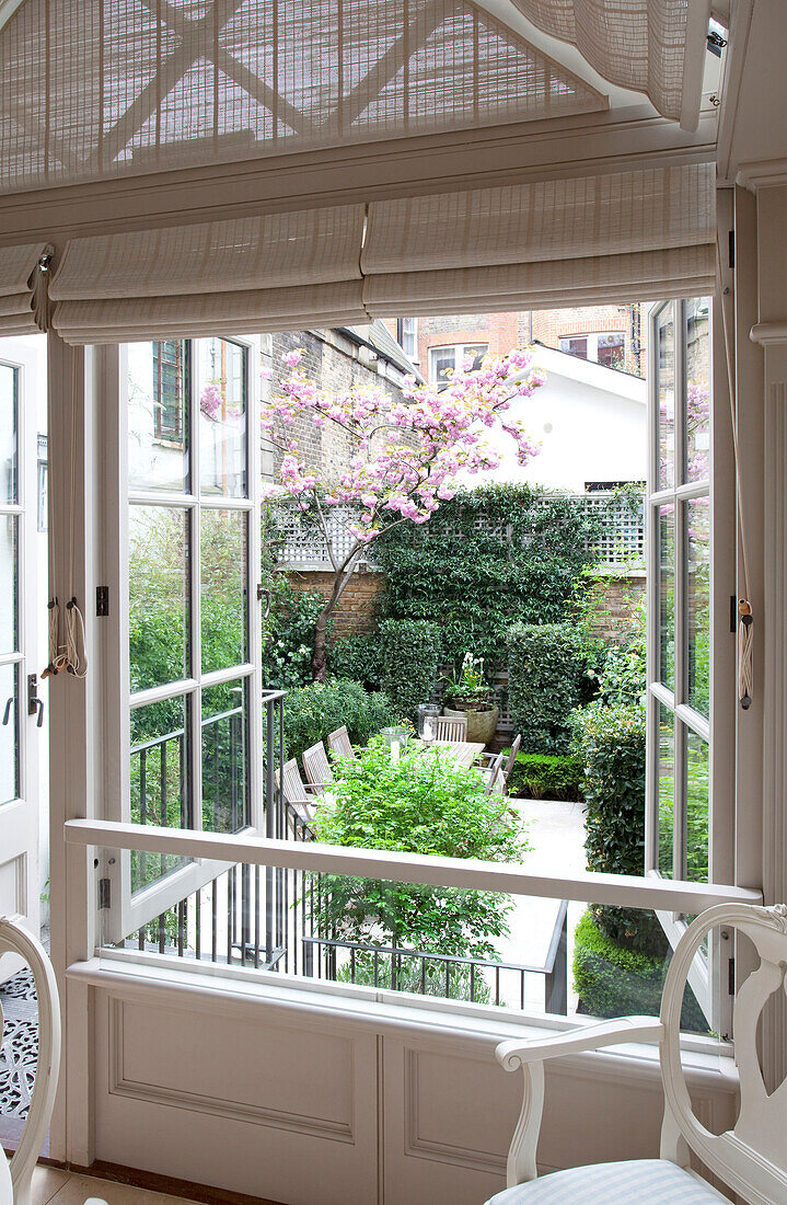 Blick durch offene Doppelfenster in den Innenhofgarten eines modernen Londoner Stadthauses, England, UK
