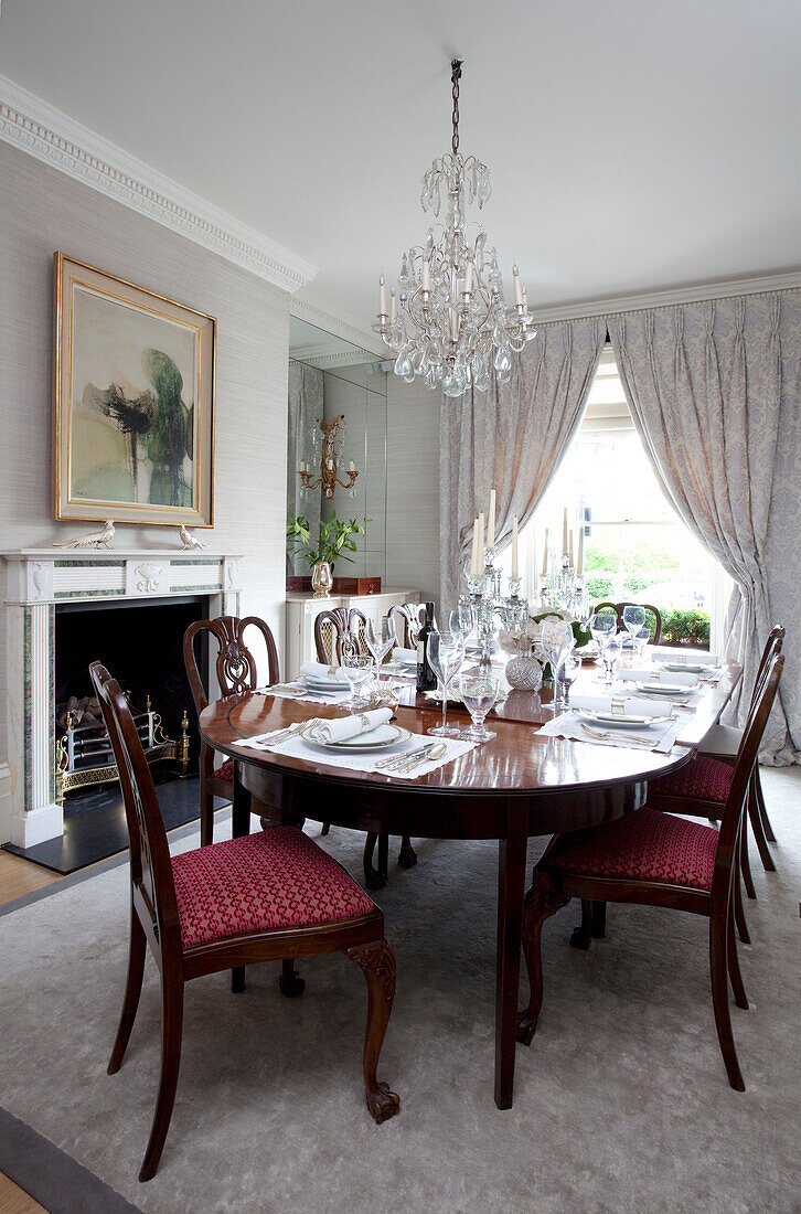 Gedeckter Esstisch mit Glaskronleuchter in einem modernen Haus in London England, UK