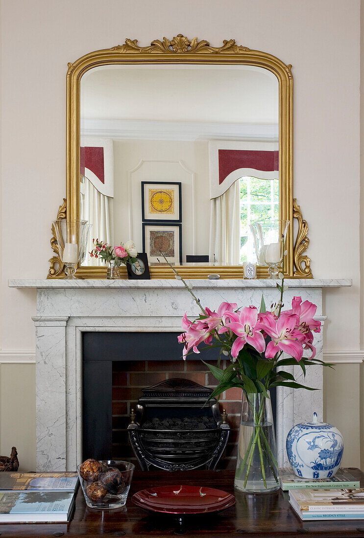Gilt mirror on marble fireplace with cut lilies in Tyne & Wear home, England, UK