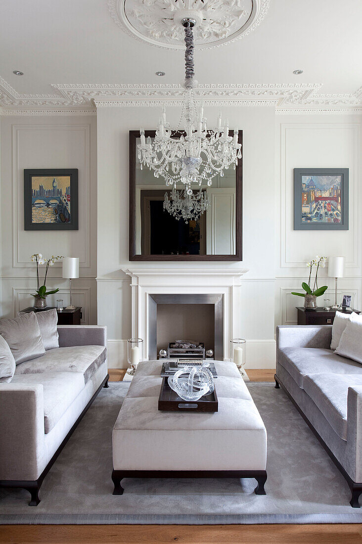 Mirror above fireplace in classic living room with glass chandelier, London townhouse, UK