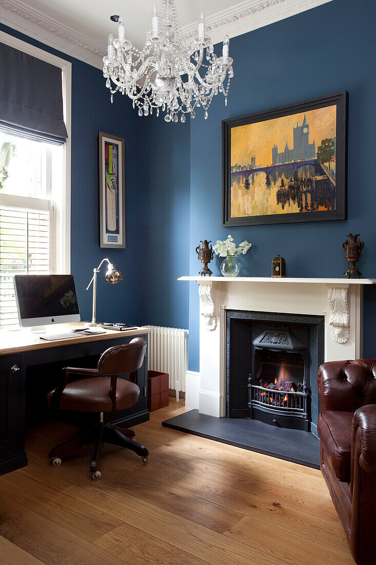 Brown leather chair at desk with computer in blue study of classic London townhouse, UK