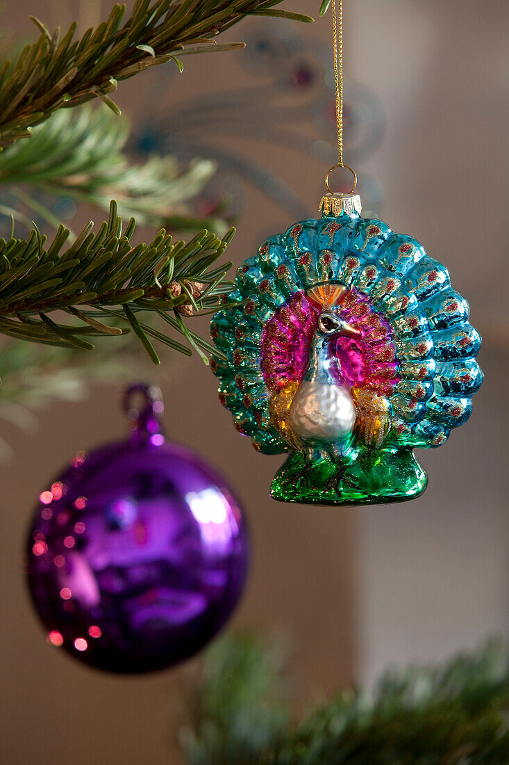Two Christmas baubles hang from Christmas tree in London home, UK