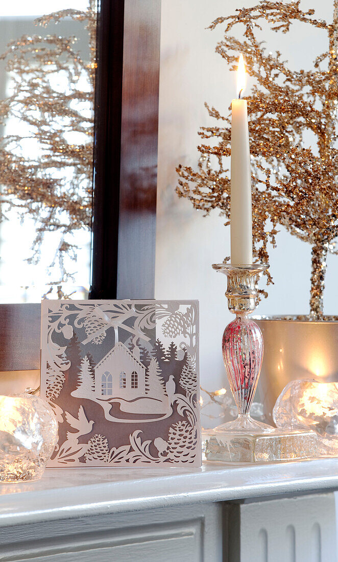 Angezündete Kerze mit Weihnachtskarte auf dem Kaminsims eines Londoner Hauses, UK