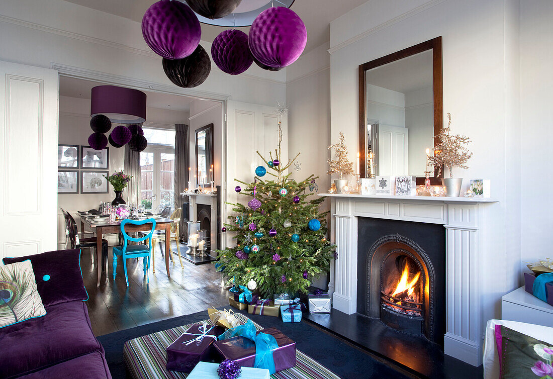 Weihnachtsbaum mit violettem Schmuck und beleuchtetem Feuer in einem Doppelzimmer eines viktorianischen Hauses in London, UK