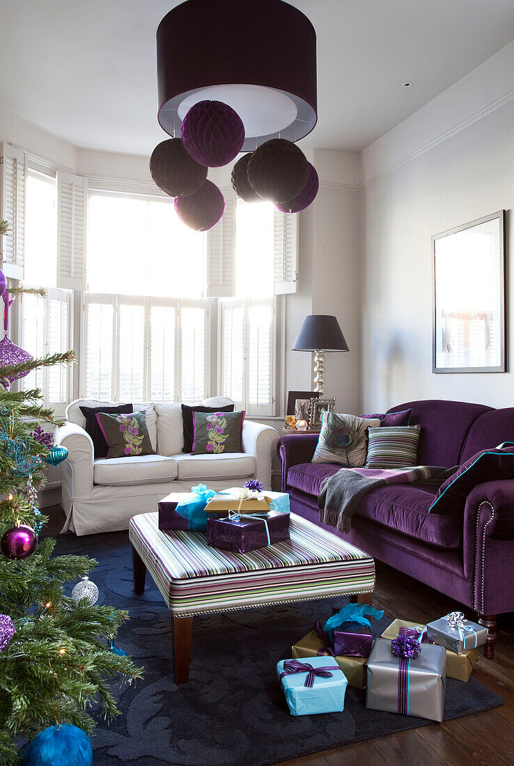 Christmas presents on floor near striped ottoman in living room of contemporary London home, UK