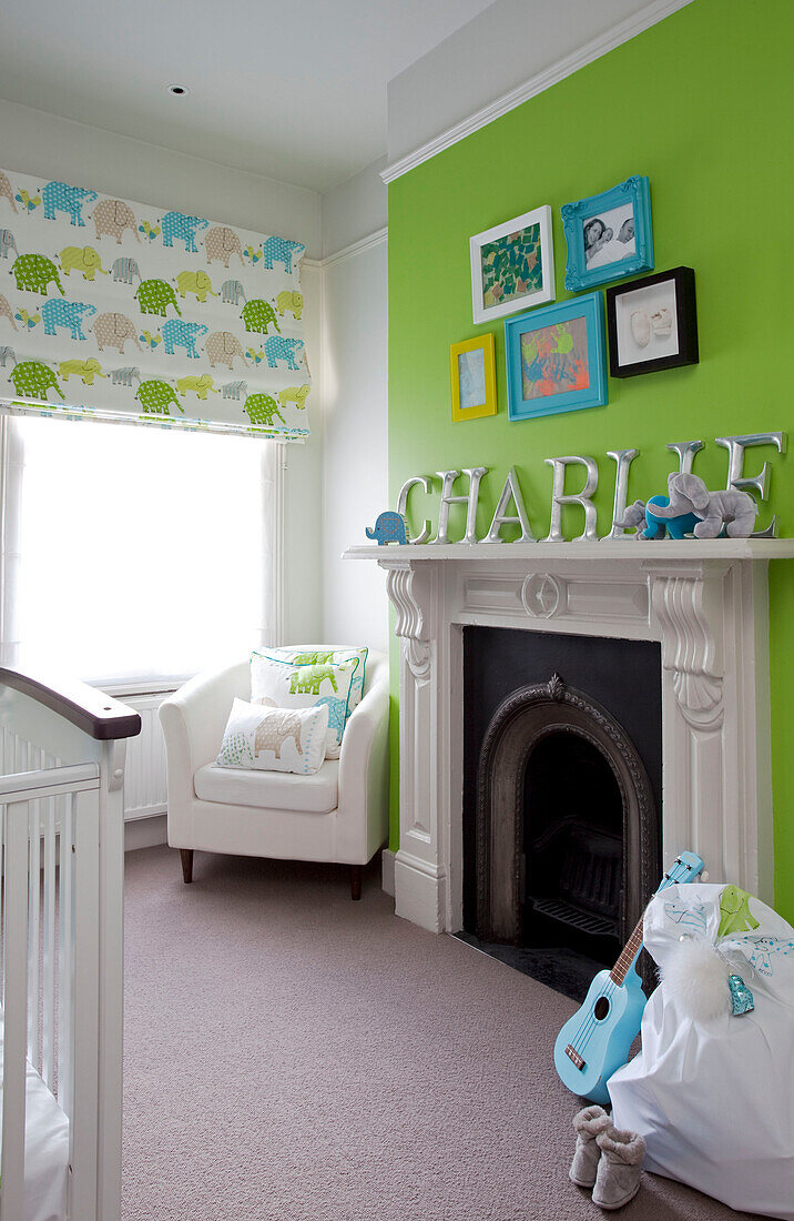 White armchair at fireplace in lime green child's nursery of contemporary London home, UK