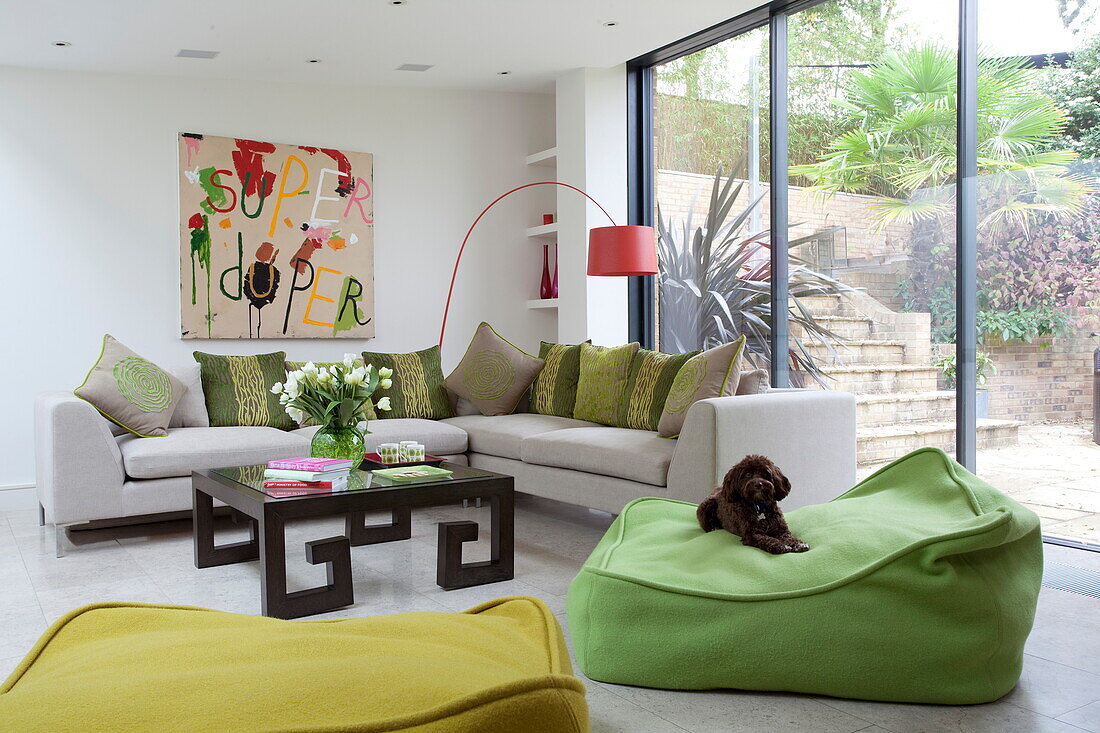 Lindgrüne Sitzmöbel mit Bogenlampe und Leinwand in einem modernen Haus in London, England, UK