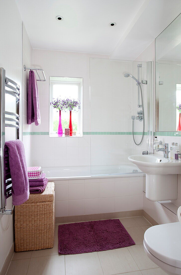 Purple towels and wicker laundry basket in bathroom of contemporary London home, England, UK