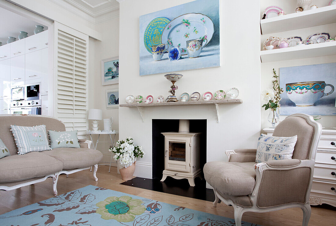 Umfangreiche Sammlung von Porzellan und Leinwand über dem Holzofen im Wohnzimmer eines Londoner Hauses, UK