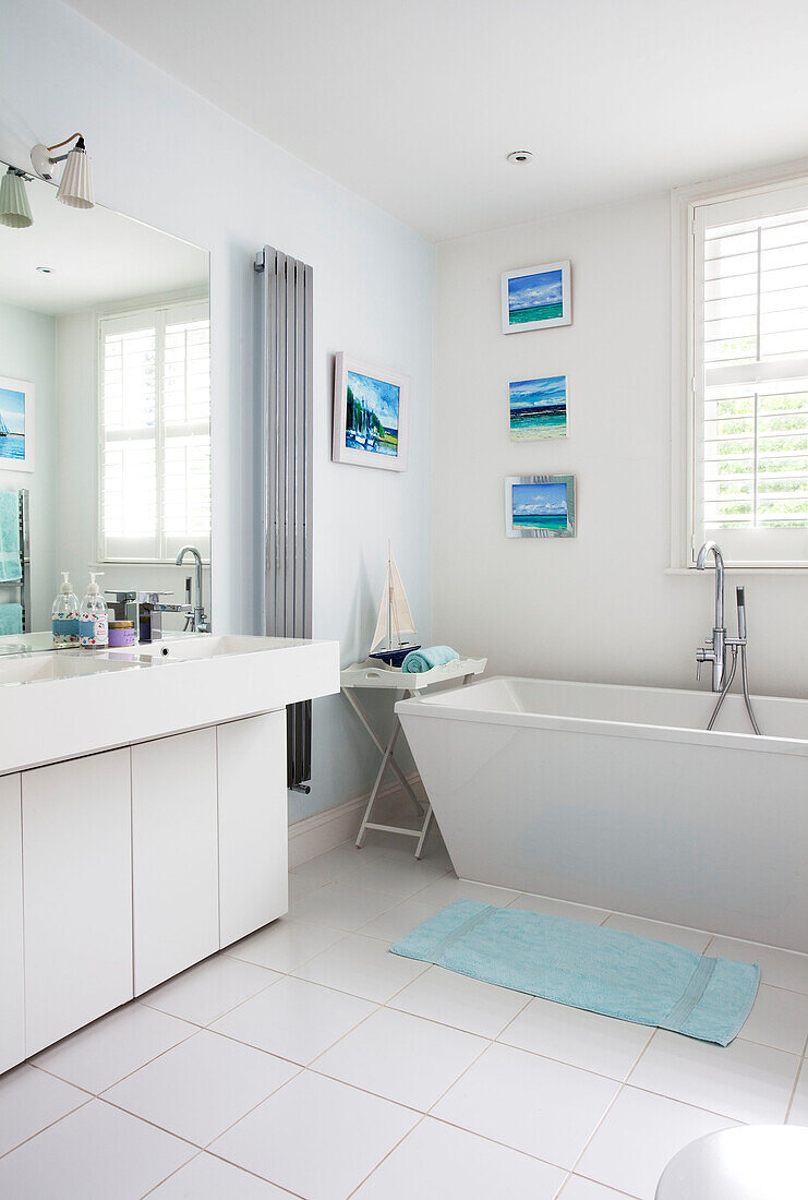 Weißes Badezimmer mit großem Spiegel und nautischem Kunstwerk in einem modernen Londoner Haus, UK