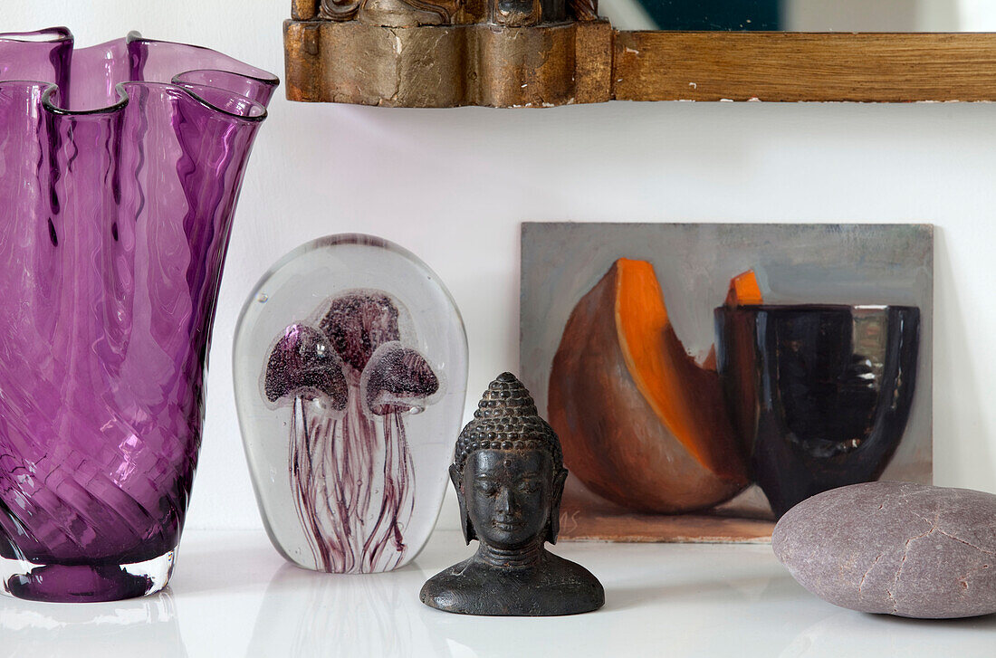 Violette Vase und Briefbeschwerer mit Kunstwerk und Buddha-Kopf in einem modernen Haus in London, UK