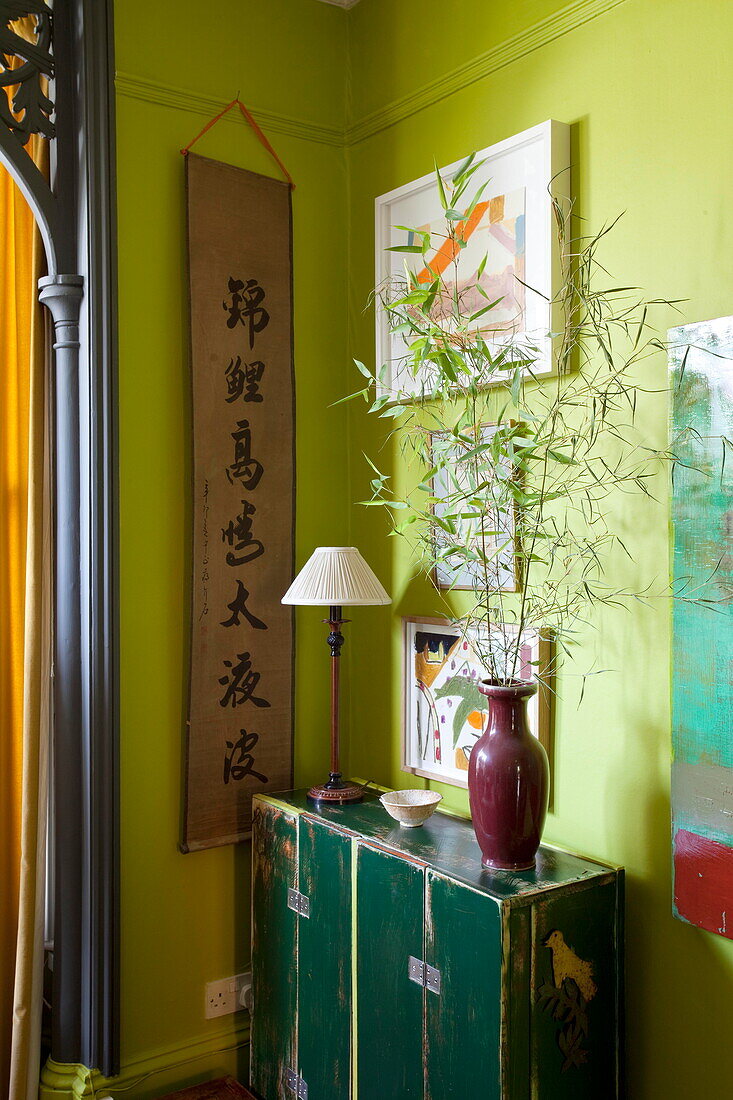 Kalligrafie-Wandbehang und Kunstwerk mit grünem Schrank im Wohnzimmer eines Londoner Hauses in England UK