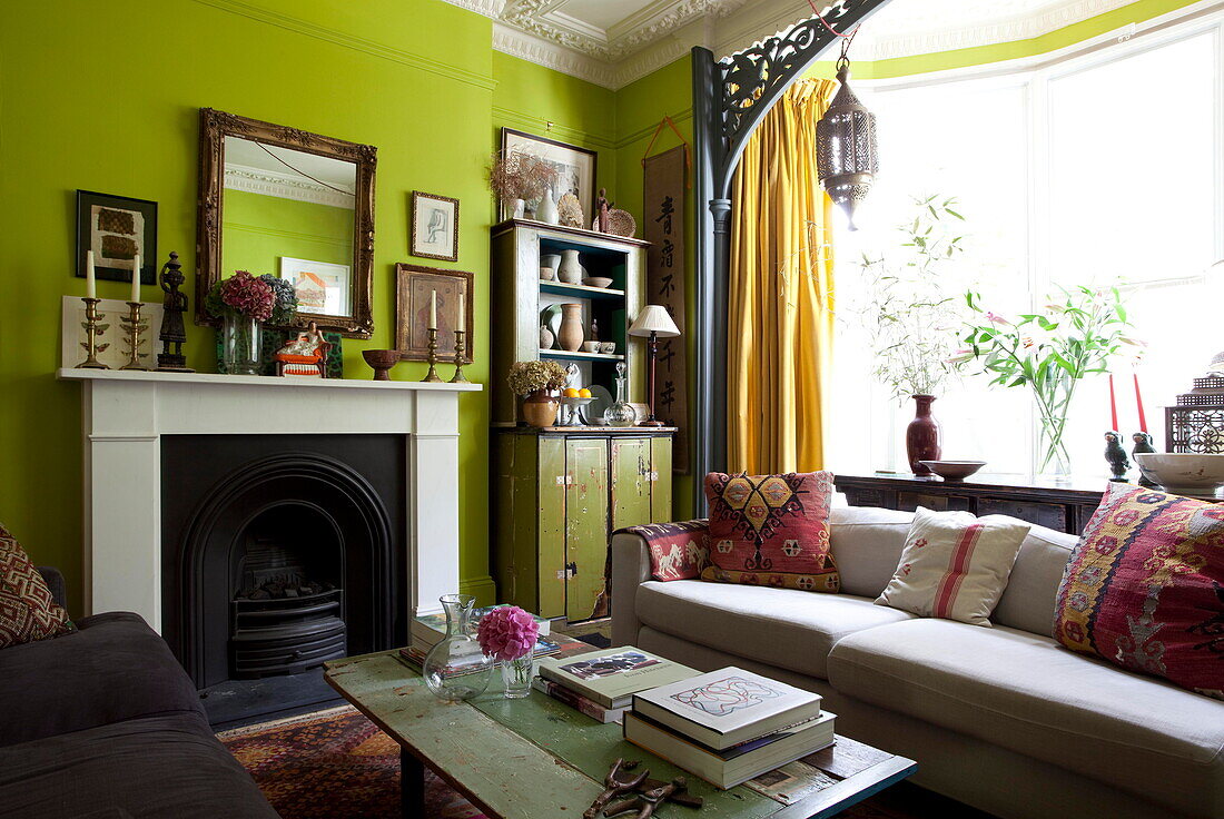 Natural light in bay window of lime green living room of London home England UK