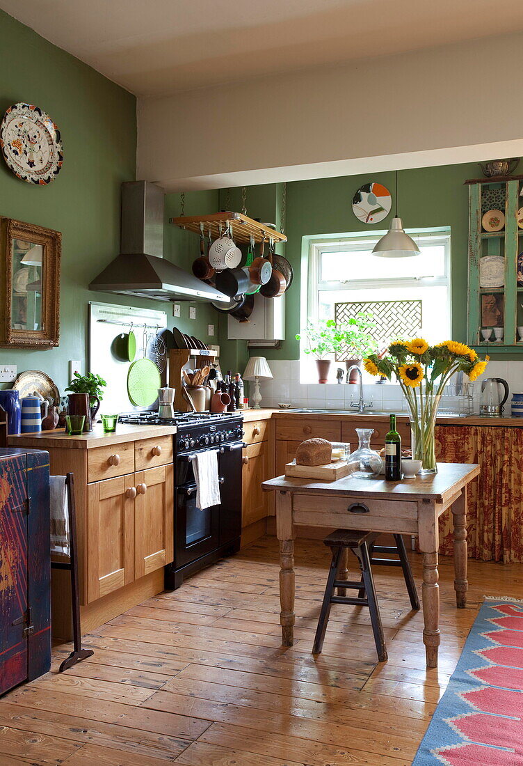 Wood fitted kitchen with sunflowers on table in London home England UK
