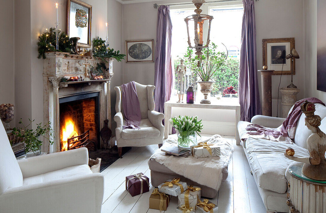 Lilac furnishings in white living room with open fire in London home, England, UK