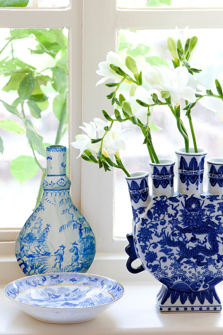 Single stem flowers in blue and and white chinaware on Sussex farmhouse windowsill, England, UK