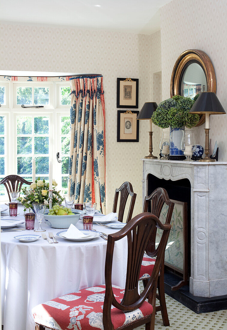 Dining chairs at table with marble fireplace in Sussex farmhouse, England, UK