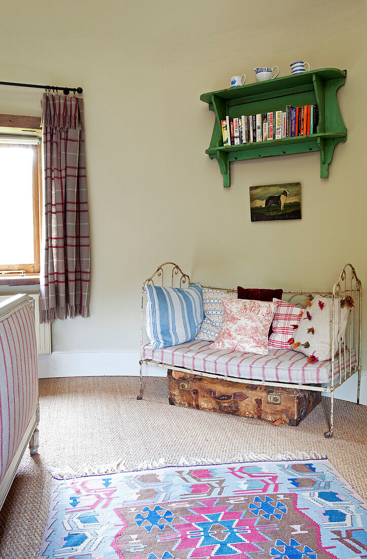 Zweisitzer-Tagesbett aus Metall mit grünem Wandbuchregal im Schlafzimmer eines Bauernhauses in Kent, England UK