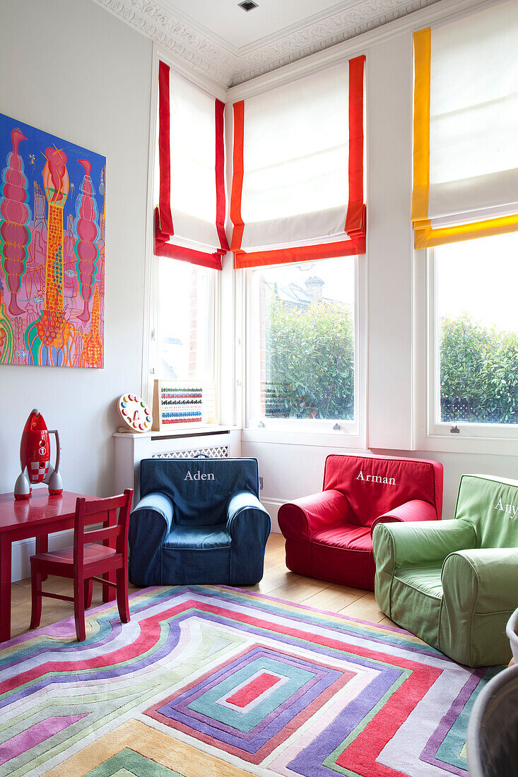 Brightly coloured, named chairs in bay window of contemporary London family home, UK