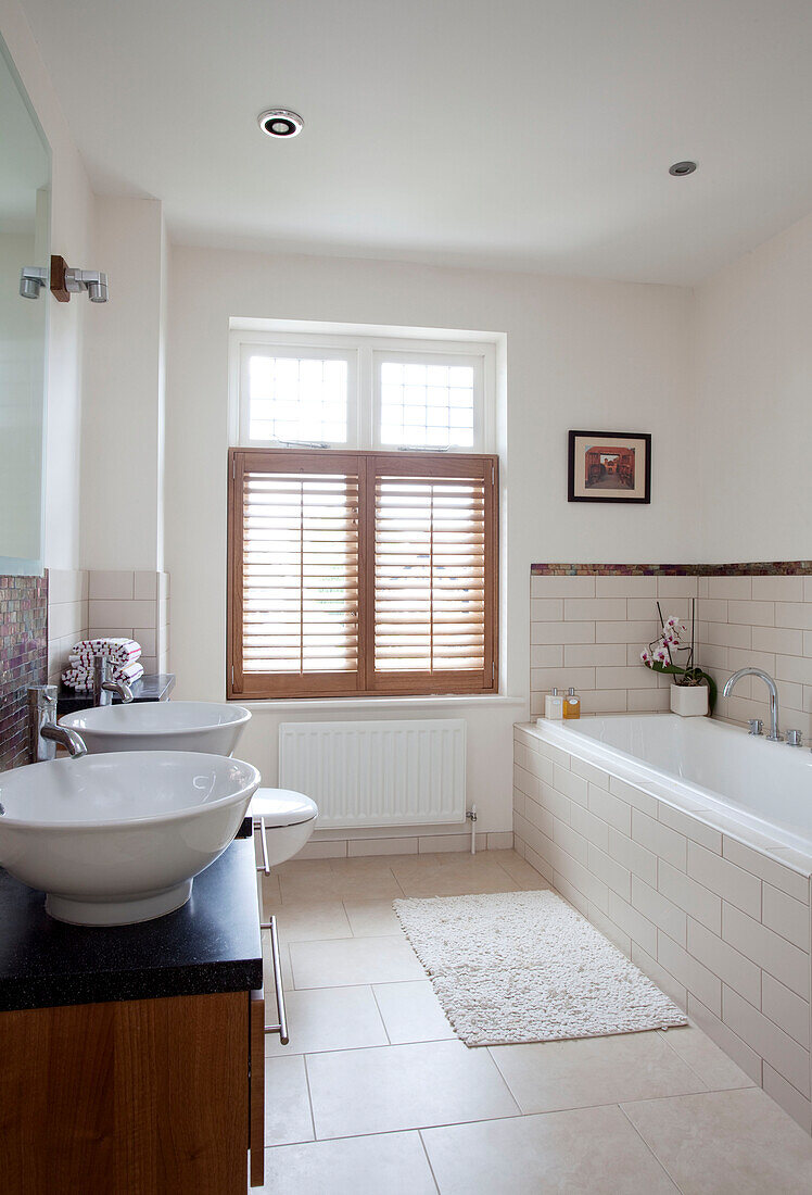 Double basin in cream tiled bathroom of Herefordshire family home England UK