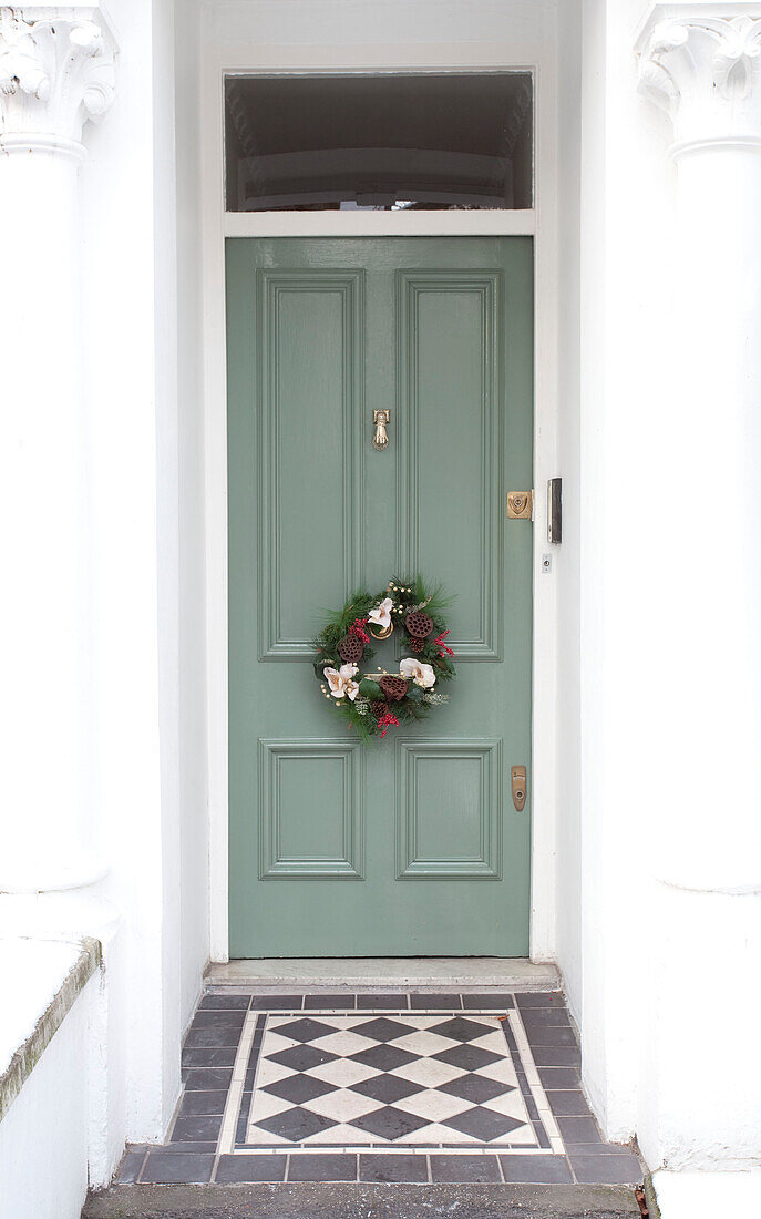 Green London townhouse front door with floral wreath, UK