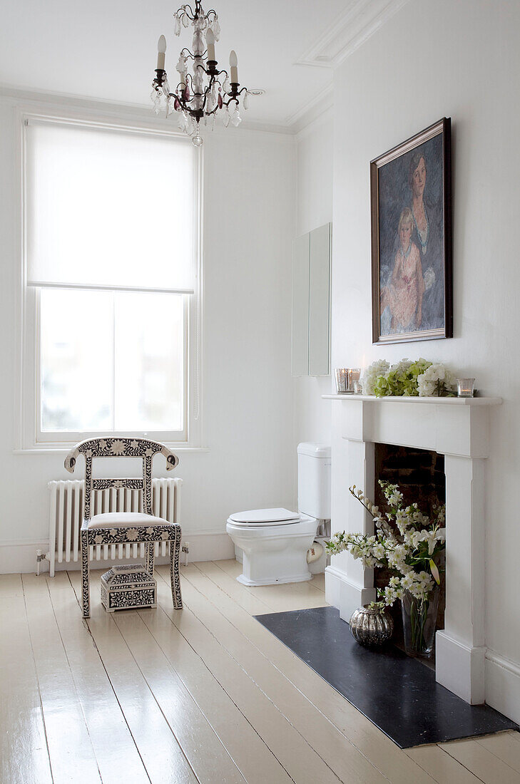 Weißes Badezimmer mit Blumen im Kamin unter einem Ölgemälde in einem Londoner Stadthaus, UK