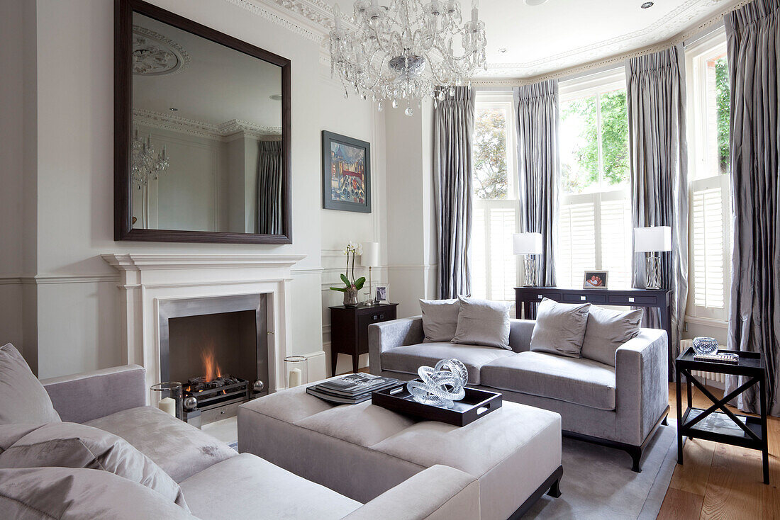 Large mirror above fireplace in classic living room of London townhouse, UK