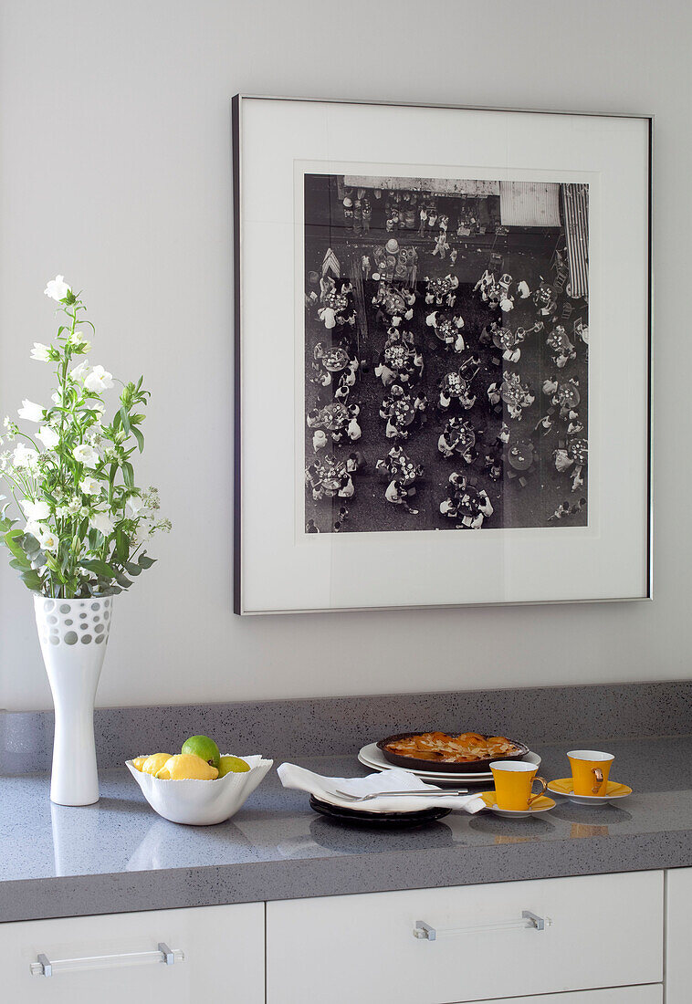 Haushaltswaren und Schnittblumen mit Kunstwerken und grauer Küchentheke in einer Londoner Wohnung, UK