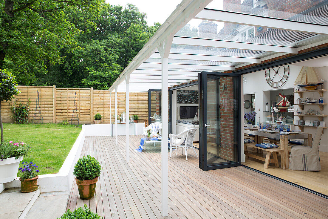 Langer Esstisch im offenen Wohnbereich mit Doppelflügeltüren mit Blick auf den Garten in einem Haus in Dulwich, London, Vereinigtes Königreich