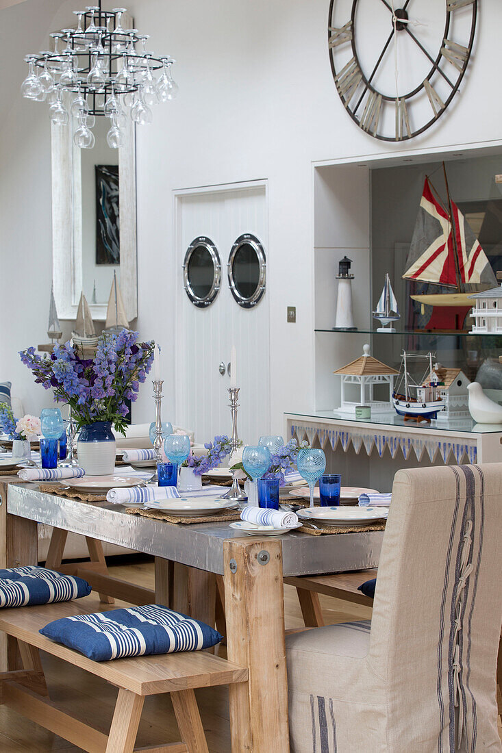 Maritimes Esszimmer mit blau-weiß gedecktem Tisch, Bullaugen in der Tür, großer Wanduhr und Kronleuchter aus Weinglas, Haus in Dulwich, London, Vereinigtes Königreich
