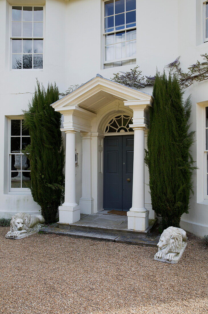 Nadelbäume auf beiden Seiten der Veranda eines Landhauses in Sussex England UK